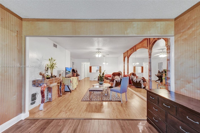 living room featuring a chandelier, a textured ceiling, light hardwood / wood-style floors, and crown molding