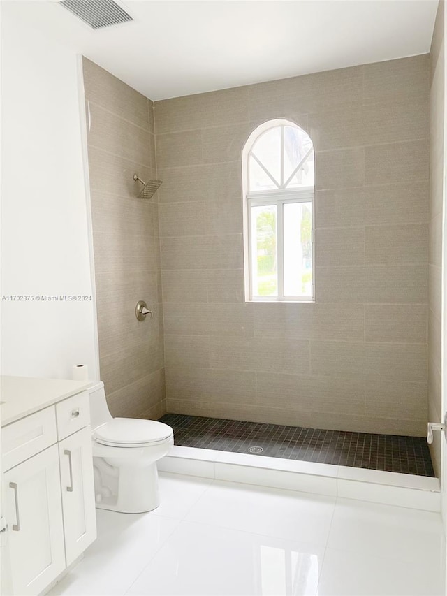 bathroom with tile patterned floors, toilet, vanity, and tiled shower