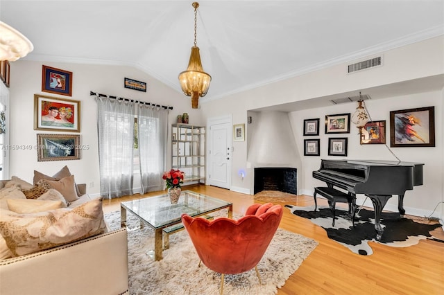 living room with crown molding, hardwood / wood-style floors, vaulted ceiling, and a notable chandelier