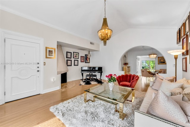 living room featuring crown molding, an inviting chandelier, vaulted ceiling, and hardwood / wood-style flooring