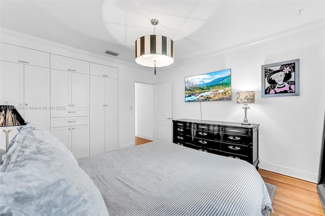 bedroom with light hardwood / wood-style floors, crown molding, and a closet