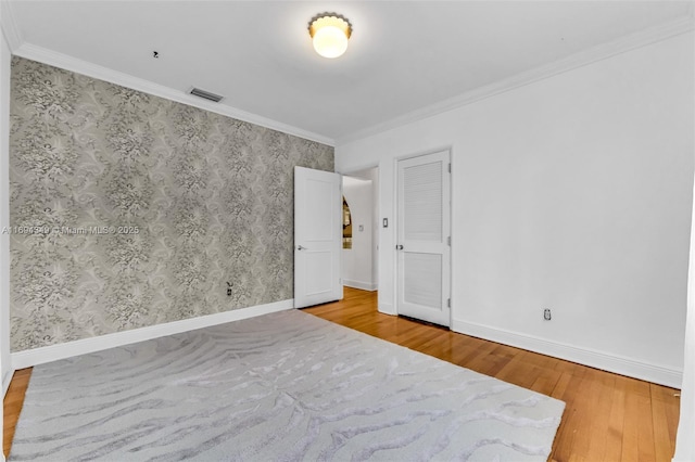 unfurnished room with light wood-type flooring and crown molding