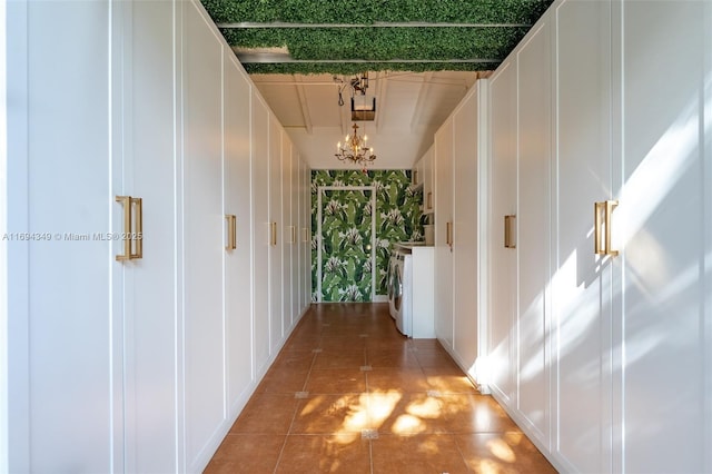 hallway with a chandelier, washer / dryer, and tile patterned flooring