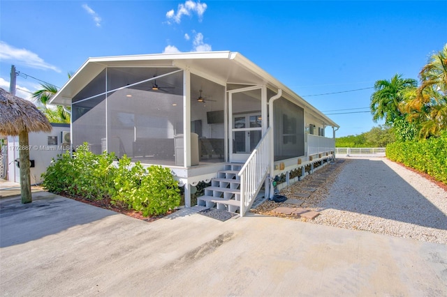 view of side of home featuring a sunroom and ceiling fan