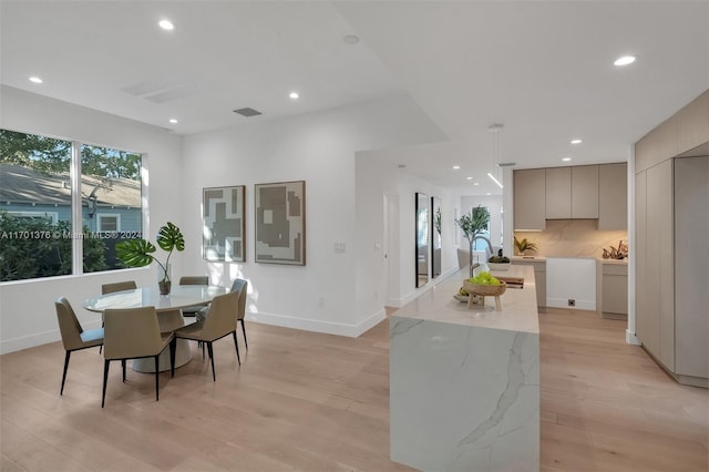 kitchen with a center island, light hardwood / wood-style flooring, gray cabinetry, and light stone counters