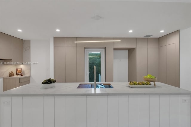 kitchen featuring gray cabinets, light stone counters, and sink