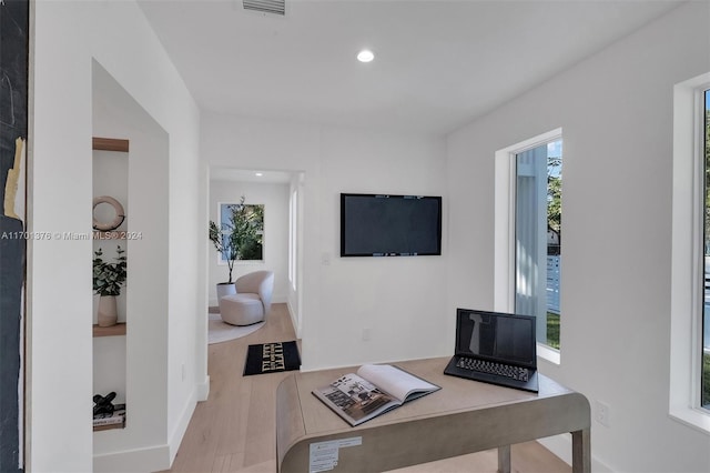 home office with light wood-type flooring and a healthy amount of sunlight