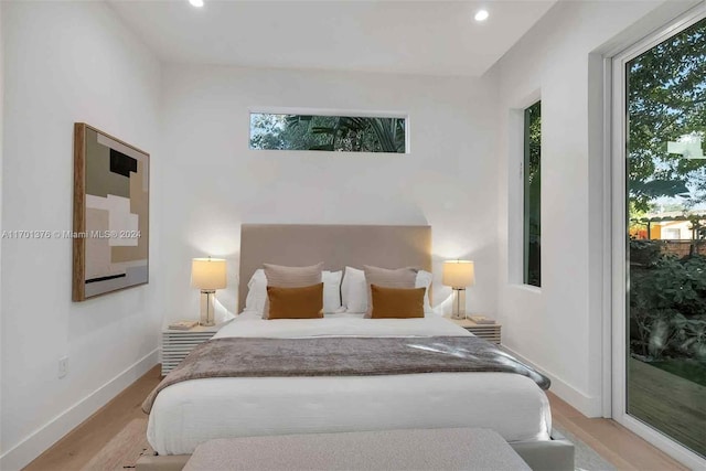 bedroom with access to exterior, light wood-type flooring, and multiple windows