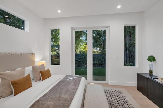 bedroom with access to outside, multiple windows, and light wood-type flooring