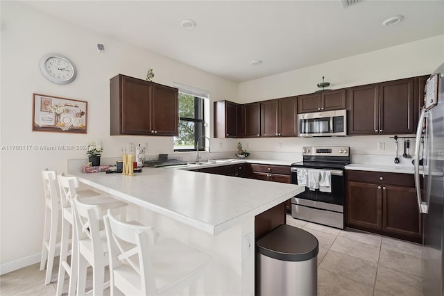 kitchen with a kitchen breakfast bar, sink, kitchen peninsula, and stainless steel appliances