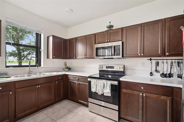 kitchen featuring light tile patterned flooring, dark brown cabinetry, sink, and appliances with stainless steel finishes