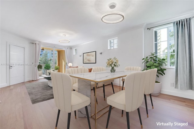 dining space featuring crown molding and light wood-type flooring