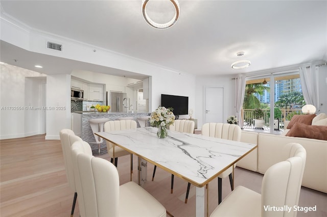 dining space featuring light hardwood / wood-style floors and crown molding