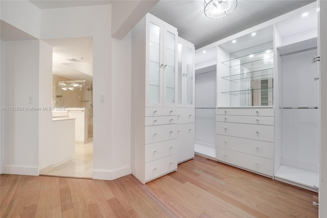 walk in closet with light hardwood / wood-style floors