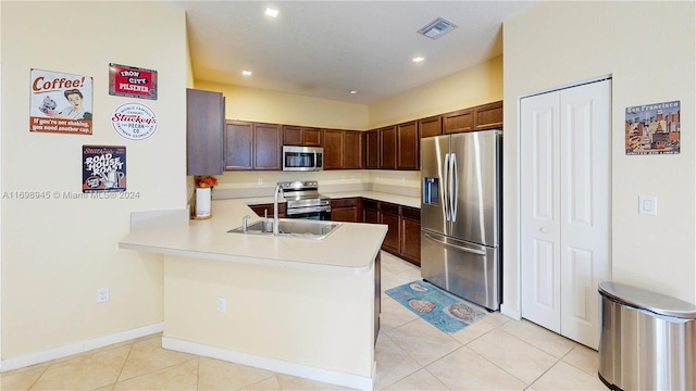 kitchen with light tile patterned floors, kitchen peninsula, sink, and appliances with stainless steel finishes