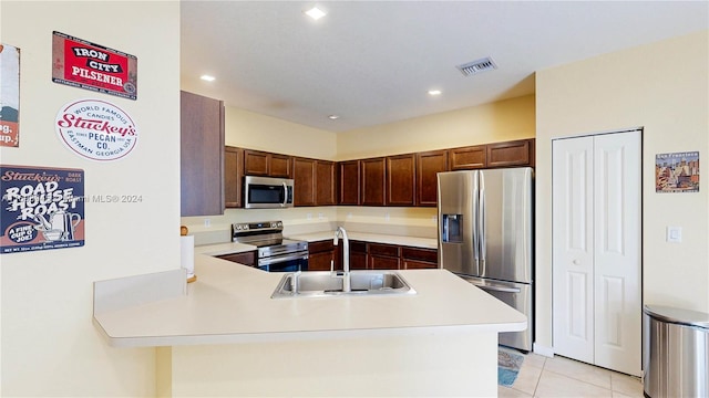 kitchen featuring light tile patterned floors, kitchen peninsula, sink, and appliances with stainless steel finishes