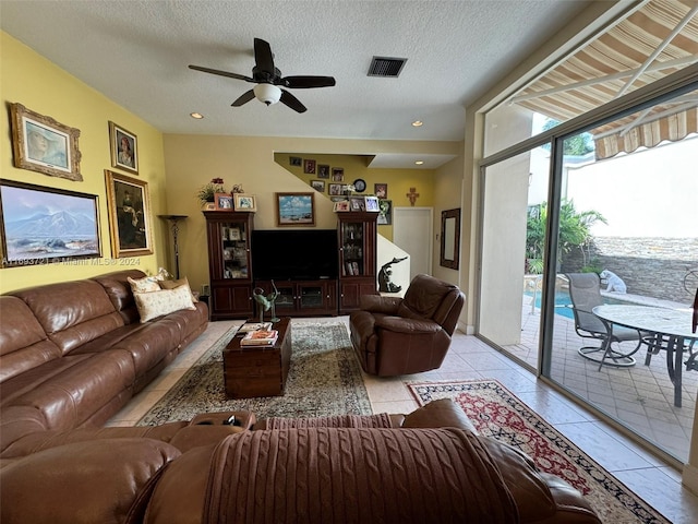 tiled living room with ceiling fan and a textured ceiling