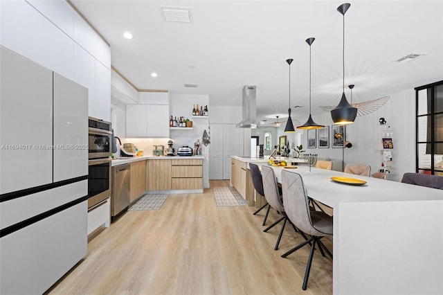 kitchen with a kitchen bar, white cabinetry, stainless steel dishwasher, pendant lighting, and a large island