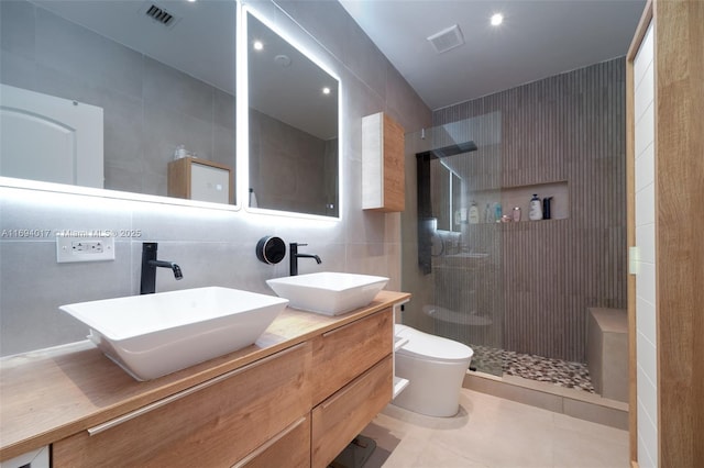 bathroom with a tile shower, tasteful backsplash, tile walls, vanity, and toilet