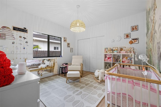 bedroom featuring a crib, a closet, and light wood-type flooring