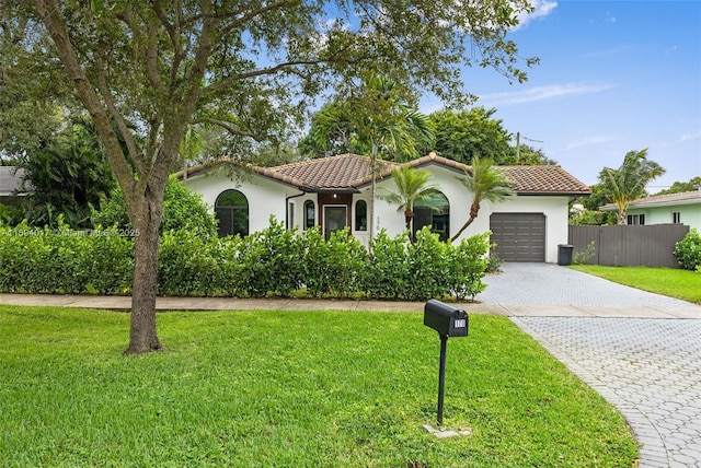 mediterranean / spanish house featuring a garage and a front yard