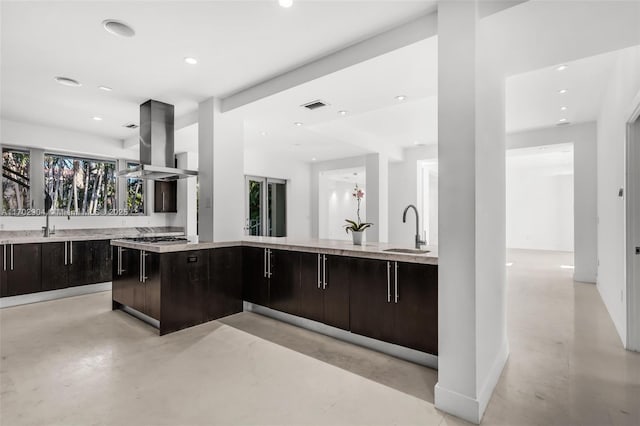 kitchen with sink, stainless steel gas stovetop, island range hood, and dark brown cabinetry