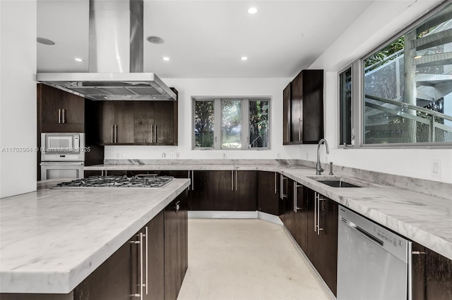 kitchen with sink, stainless steel appliances, island range hood, and dark brown cabinetry