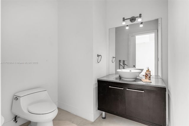 bathroom with toilet, vanity, and tile patterned flooring