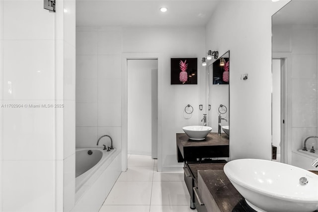 bathroom featuring tile patterned flooring, tiled bath, and vanity