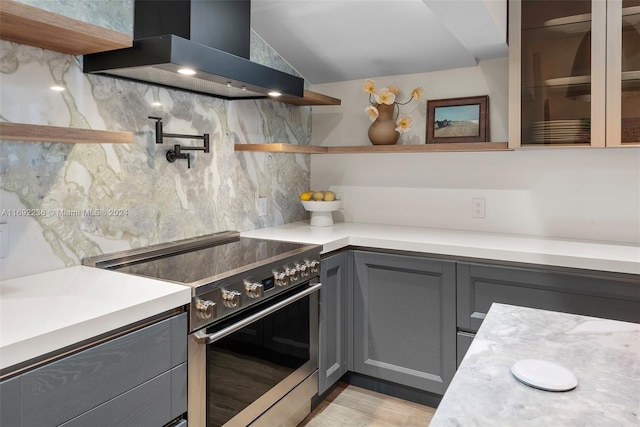 kitchen featuring wall chimney range hood, light hardwood / wood-style flooring, backsplash, gray cabinets, and electric stove