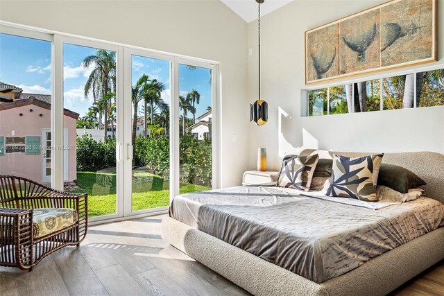 bedroom featuring multiple windows, access to exterior, lofted ceiling, and hardwood / wood-style flooring