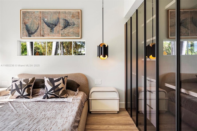 bedroom with multiple windows and wood finished floors