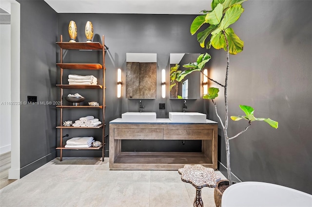 full bathroom with double vanity, baseboards, and a sink