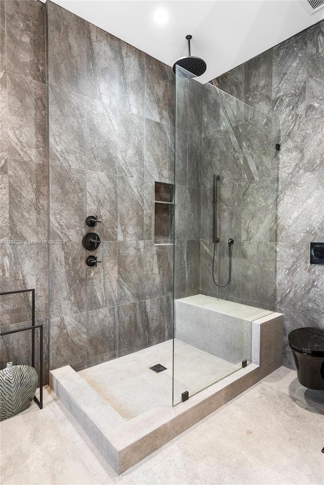 bathroom featuring a tile shower, tile walls, and toilet