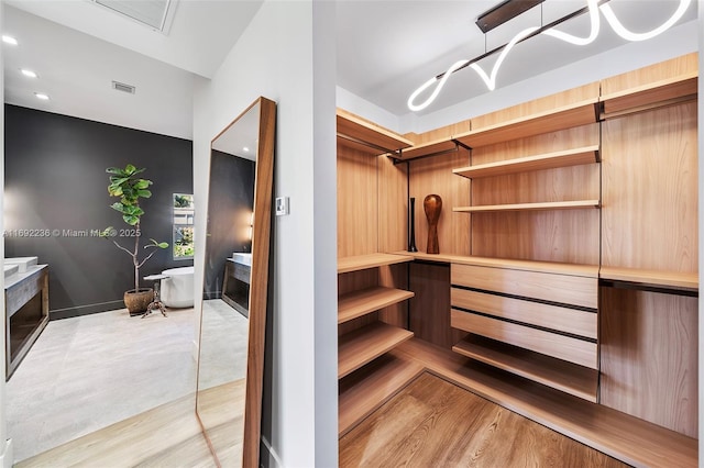 spacious closet with visible vents, a fireplace, and light wood-type flooring