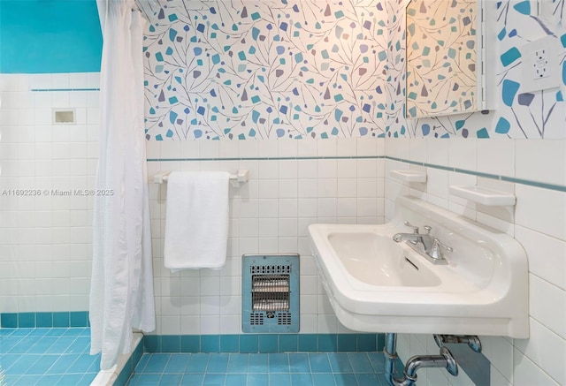 bathroom with a tile shower, heating unit, tile walls, and a sink