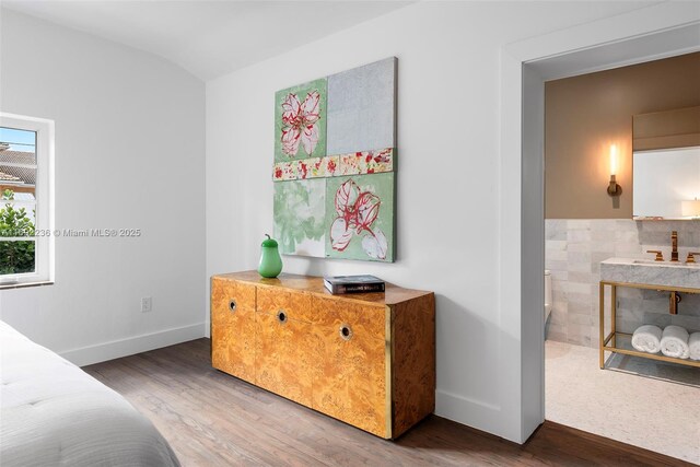 bedroom with lofted ceiling, sink, dark wood-type flooring, and tile walls