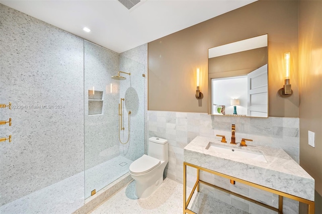 bathroom featuring tiled shower, toilet, tile walls, and vanity