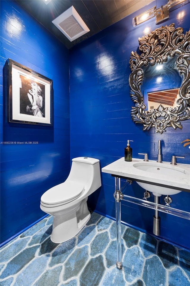 bathroom with toilet, visible vents, and a sink