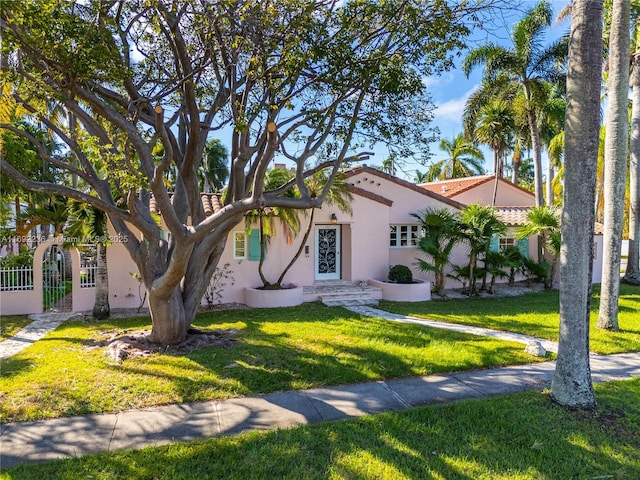 view of front of house with stucco siding, a front yard, and a tile roof