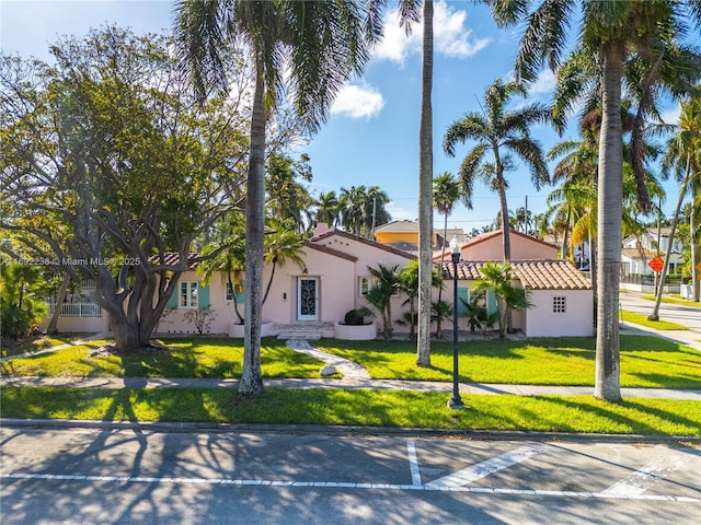 mediterranean / spanish house with stucco siding and a front lawn