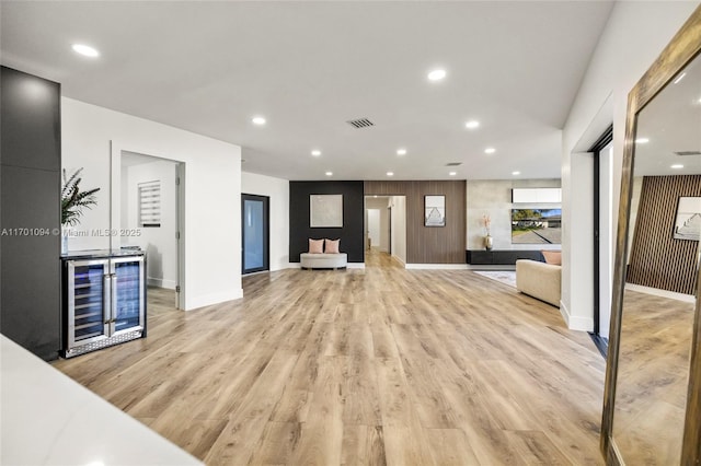 unfurnished living room with baseboards, light wood finished floors, wine cooler, and recessed lighting