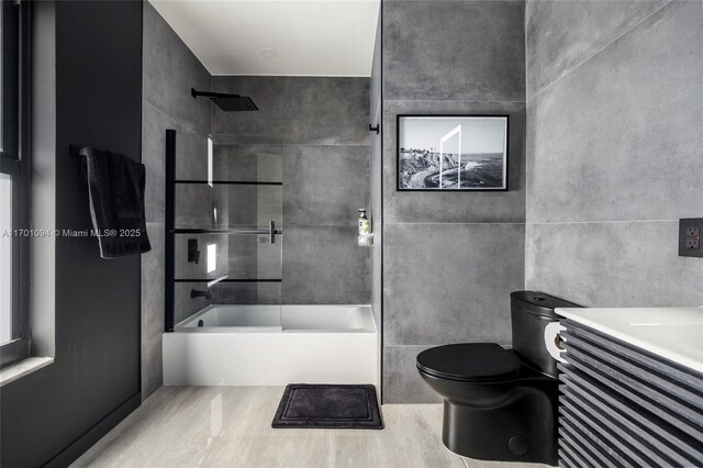 bathroom featuring toilet, tile walls, and shower / bathtub combination