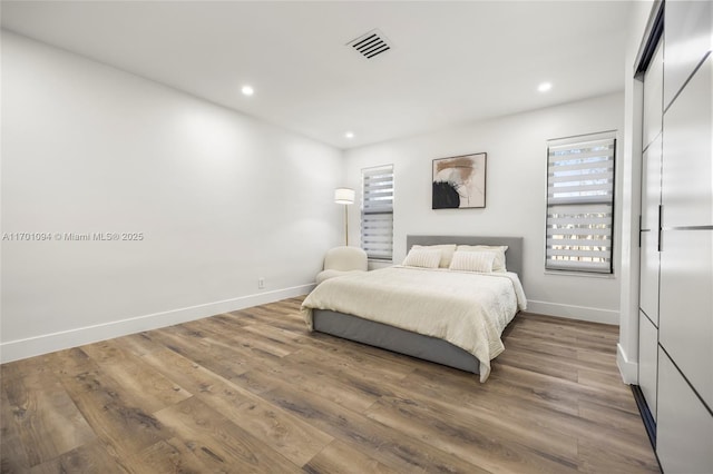 bedroom featuring visible vents, baseboards, and wood finished floors