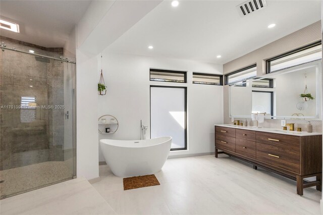 bathroom featuring double vanity, recessed lighting, visible vents, a stall shower, and a freestanding tub