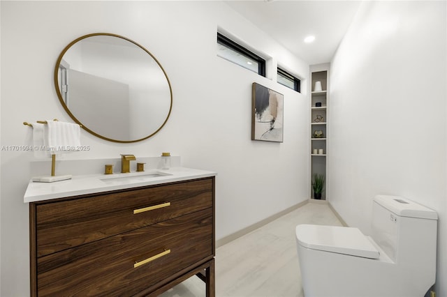 bathroom with baseboards, vanity, and toilet