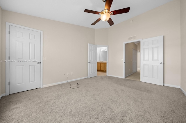 unfurnished bedroom with ceiling fan, light carpet, and ensuite bath