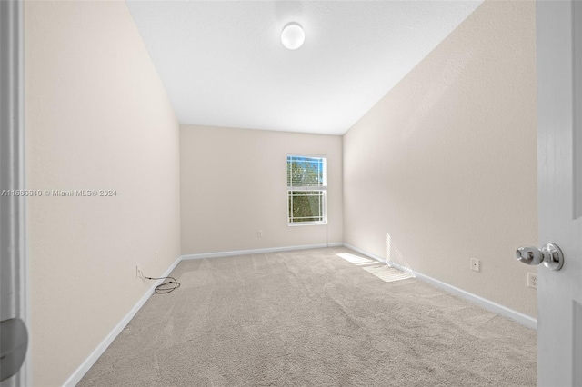 carpeted empty room with lofted ceiling