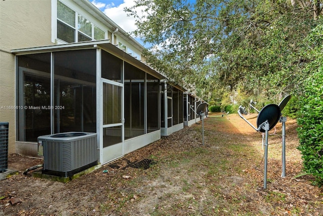 view of side of home with central AC unit and a sunroom