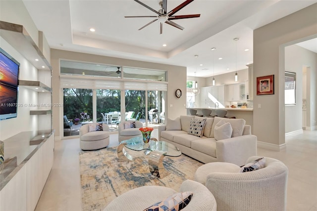 living room with ceiling fan and a raised ceiling